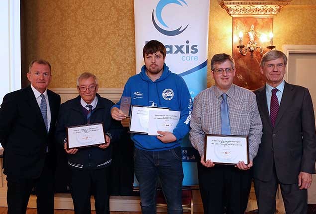 Five mine standing in front of a praxis care sign, three in the middle holding certificates 