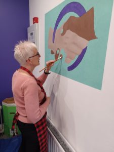 woman painting a picture of hands on a wall